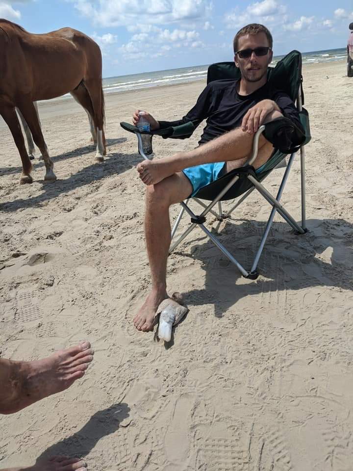 Man relaxing on the beach with a pigeon nearby