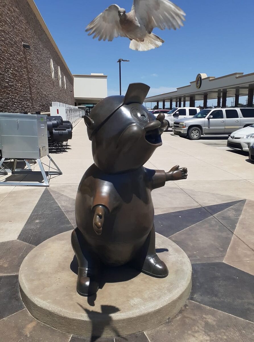 Pigeon flying near a pig statue