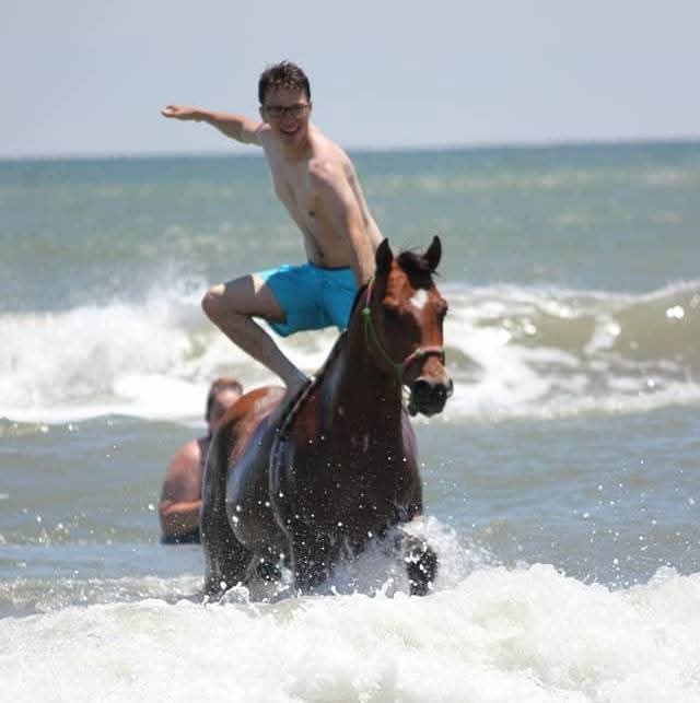 Man standing on a horse in the ocean waves