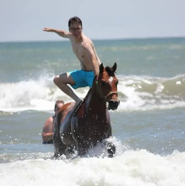 Man standing on a horse in the ocean waves